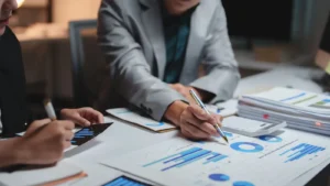 Business professionals reviewing charts and financial documents at a desk, illustrating digital transformation and IFRS compliance